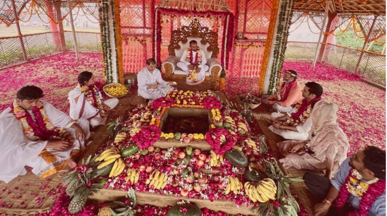 HH Paramguruji seated at the sacred fire ceremony, surrounded by participants, fruit offerings, and rose petals — Sattva Shuddhi retreat